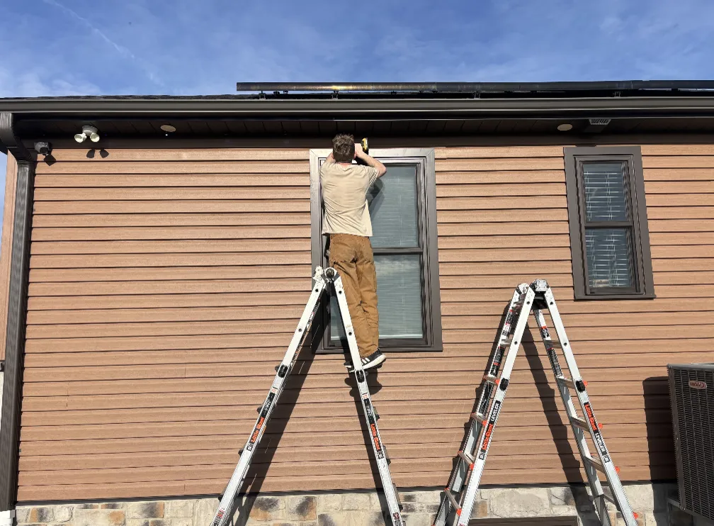 Mason-Dixon LED Co. installer on a ladder mounting permanent lighting along a home's eave